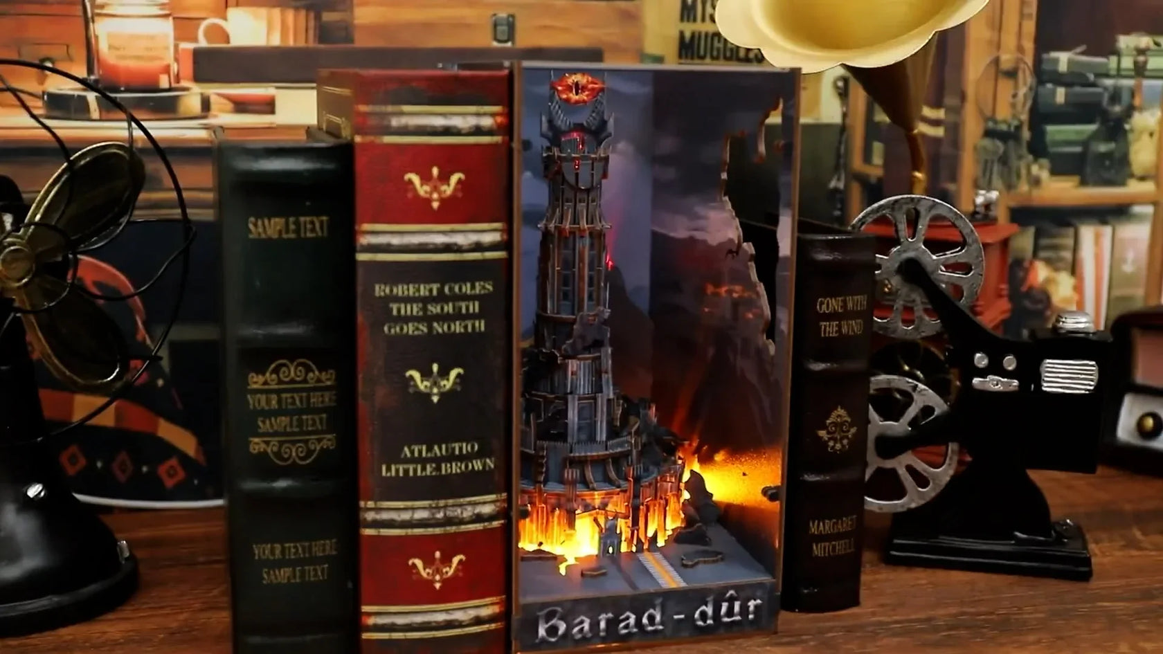 Buchstütze mit beleuchtetem Modell des Turms Barad-dûr zwischen zwei Büchern