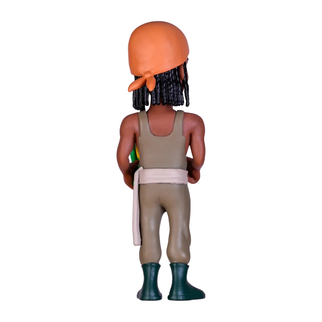 Rueckansicht einer Spielfigur mit orangefarbenem Kopftuch und dunklen Zöpfen in beiger Kleidung