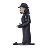 Sammelfigur von The Undertaker in schwarzem Mantel und Hut von der Seite