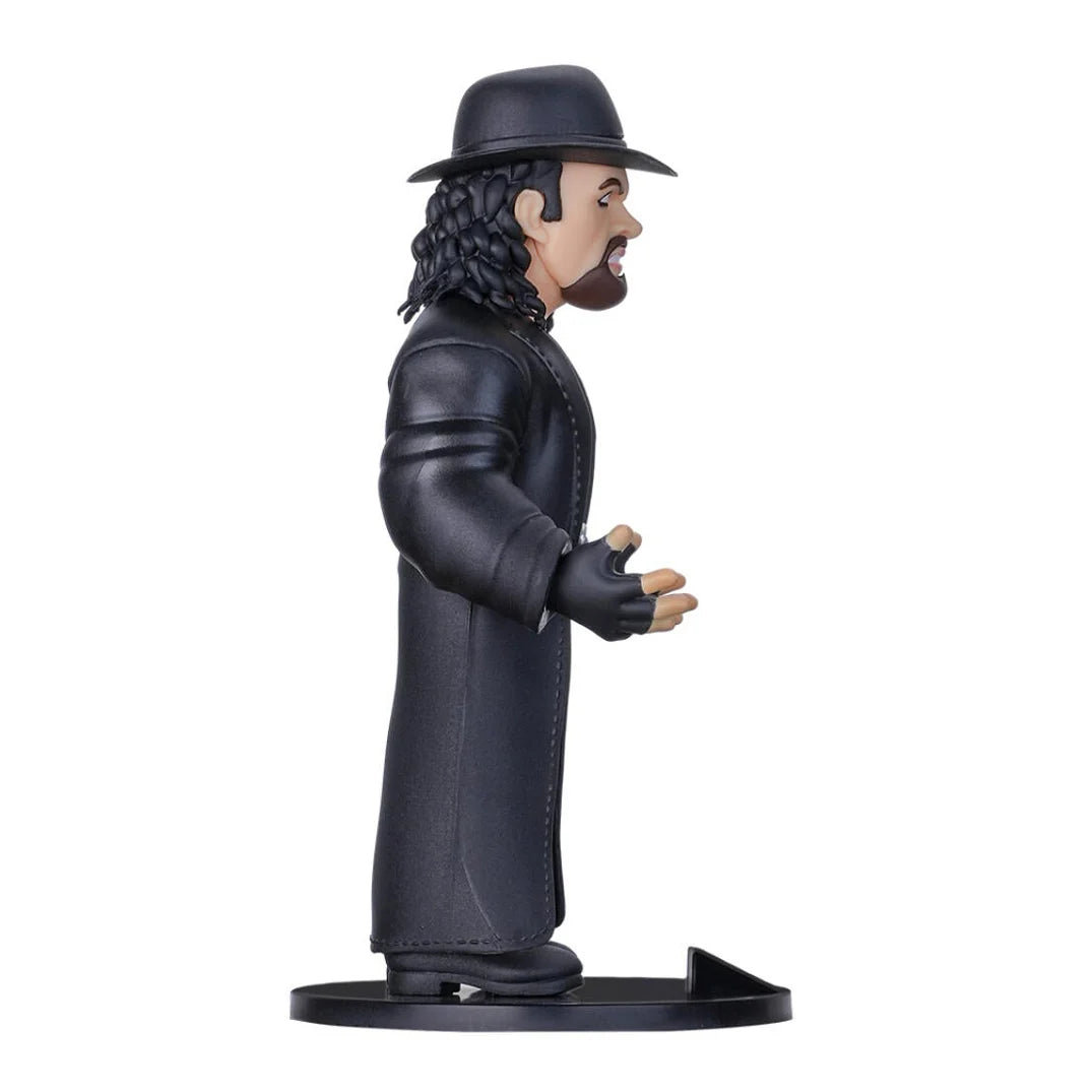 Sammelfigur von The Undertaker in schwarzem Mantel und Hut auf einem runden Sockel