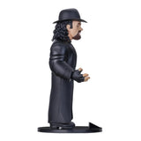 Sammelfigur von The Undertaker in schwarzem Mantel und Hut auf einem runden Sockel