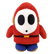 Plüschfigur Shy Guy in rotem Gewand mit weißer Maske und blauen Hosen
