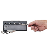 Hand steckt Fender Klinkenstecker-Schlüsselanhänger in den Pluginz Mini Twin Amp Schlüsselhalter